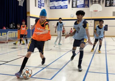 Kids playing indoor soccer in a gymnasium.