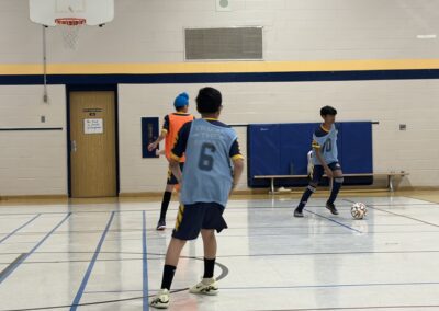 Two boys playing indoor soccer in a gymnasium.