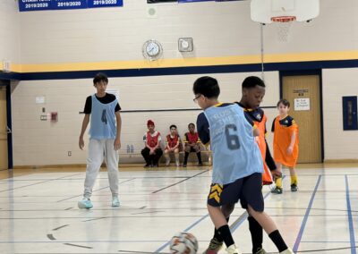 Young boys playing indoor soccer in a gym.