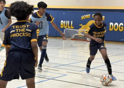 Girls playing indoor soccer in a gymnasium.